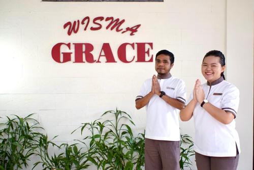 un hombre y una mujer parados frente a una señal en Wisma Grace, en Ambon