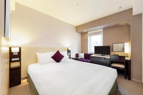 神戸市にあるKOKO HOTEL 神戸三宮の大きなベッドとデスクが備わるホテルルームです。