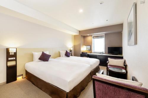 een hotelkamer met een groot bed en een bureau bij KOKO HOTEL Kobe Sannomiya in Kobe