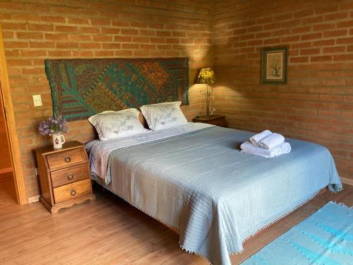 1 dormitorio con cama y pared de ladrillo en Casa Baúau en São Bento do Sapucaí