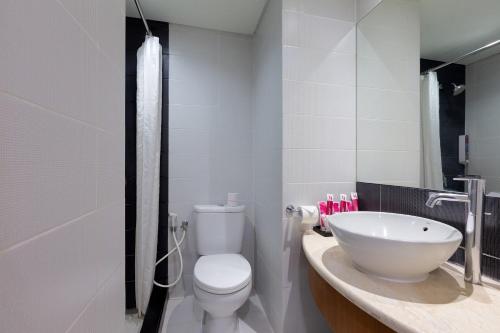 uma casa de banho com um WC branco e um lavatório. em favehotel Manahan - Solo em Surakarta