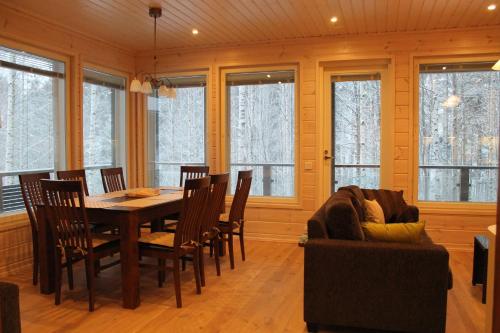 a dining room with a table and chairs and windows at SResort Family Apartment in Imatra