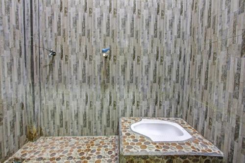 a bathroom with a toilet in the corner of a shower at SPOT ON 91771 Homestay Bang Haji in Praya