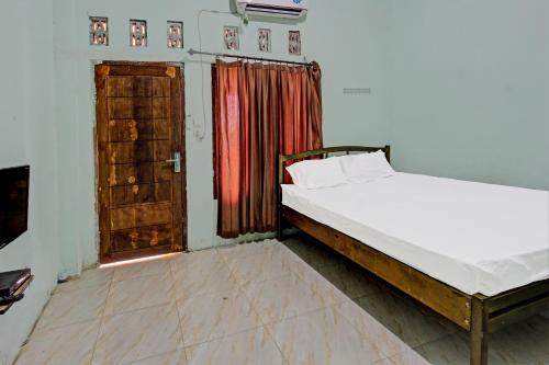a bedroom with a bed and an open door at SPOT ON 91771 Homestay Bang Haji in Praya