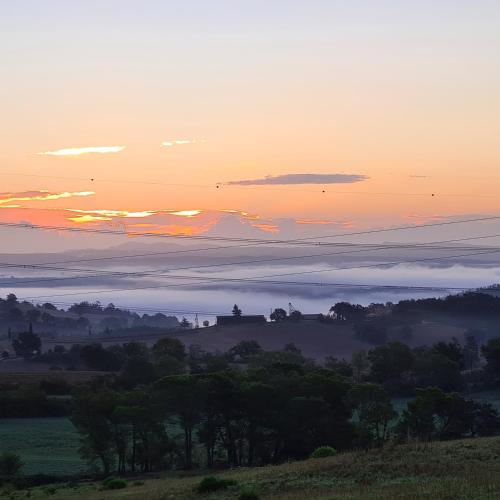 a view of a foggy field with the sun setting in the sky at Casa Carpineta in Manciano