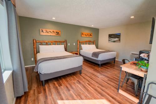 a bedroom with two beds and a table and a desk at Evergreen Motel in Libby