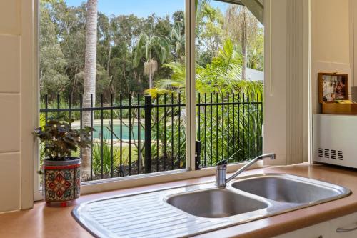 a kitchen with a sink and a large window at Treetops Lakeside Apartments in Byron Bay