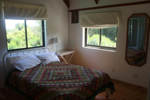 a bedroom with a bed and two windows at Fijnbosch Cottage and Camping in Stormsrivier