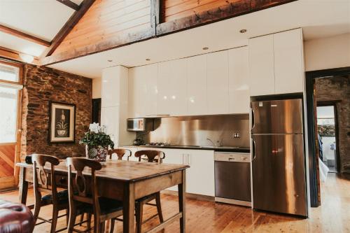 a kitchen with a wooden table and a stainless steel refrigerator at Mintaro Cottage in Mintaro