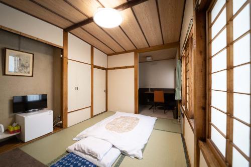 Habitación pequeña con cama y TV. en Yoshidaya Ryokan en Zao Onsen