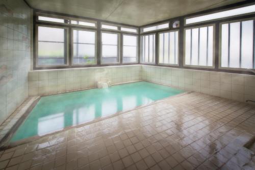 a swimming pool in a room with windows at Yoshidaya Ryokan in Zao Onsen