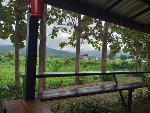 a wooden bench in front of a field with a view at Sleep & fishing Pua in Nan