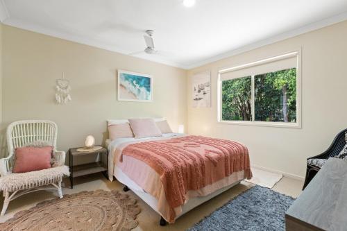 a bedroom with a bed and a window and a chair at Treetops Lakeside Apartments in Byron Bay