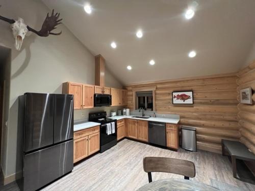 una cocina con armarios de madera y electrodomésticos de acero inoxidable en Clear creek cabin, en Seward