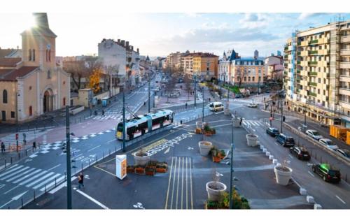 uma cidade com um autocarro numa rua com trânsito em Chambre cosy privée Villeurbanne proximité centre ville place de parking privée selon disponibilité em Villeurbanne