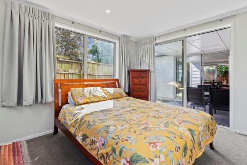 a bedroom with a bed and a large window at Campbell Road Classic - Mount Maunganui Bach in Mount Maunganui