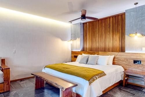 a bedroom with a large bed and a bench at Miraluna 233 at Luum Zama in Tulum