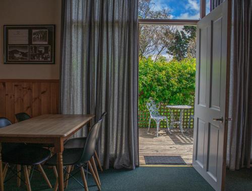 una puerta abierta a un patio con mesa y sillas en Gaol House Cottages en Bicheno