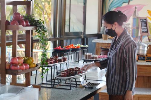 Uma mulher de máscara preparando comida em um bufê. em Sunsetfalls Gardens and Resort em Magelang