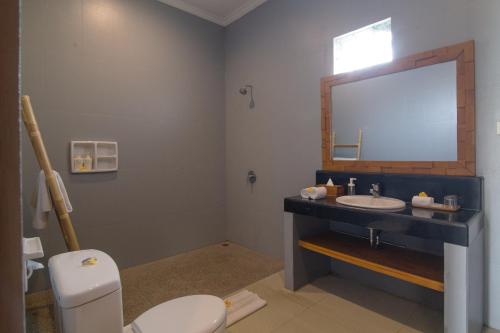 La salle de bains est pourvue de toilettes, d'un lavabo et d'un miroir. dans l'établissement Villa Verano at Echo Beach Canggu, à Canggu