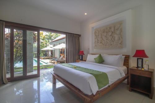 sypialnia z dużym łóżkiem i przesuwnymi szklanymi drzwiami w obiekcie Villa Verano at Echo Beach Canggu w mieście Canggu