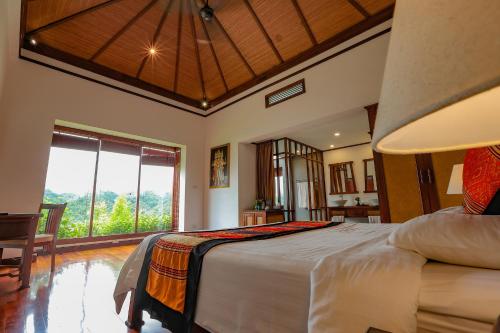 a bedroom with a large bed and a large window at Le Grand Pakbeng in Pakbeng