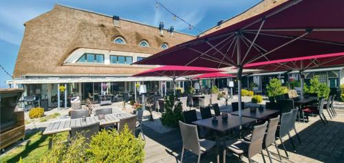 un patio extérieur avec des tables, des chaises et des parasols dans l'établissement Wittenbeck Resort, à Kühlungsborn