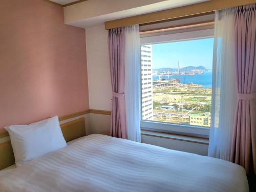 a bedroom with a bed and a large window at Toyoko-Inn Busan Jungang Station in Busan