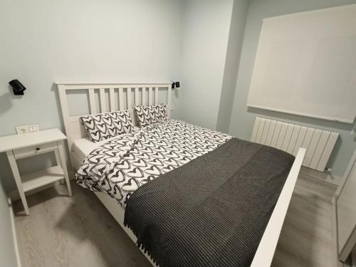 Schlafzimmer mit einem Bett mit einer schwarzen und weißen Bettdecke in der Unterkunft Cómodo apartamento en el centro de Bermeo. in Bermeo