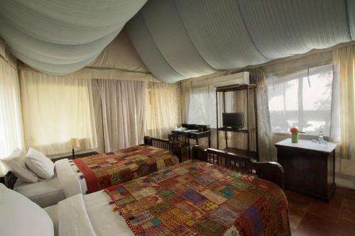 a hotel room with two beds and a television at Grassroots Wayanad, Valley-view Tents in Vythiri