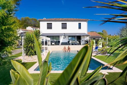 une villa avec une piscine en face d'une maison dans l'établissement Villa Quietude, à Bagnols-en-Forêt