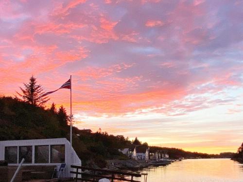 a sunset over a river with a flag on a boat at Seaside Fisherman s Haven-By Traum in Steinsbø