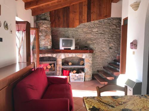 a living room with a red couch and a stone fireplace at Chaillod 2 in Saint Nicolas