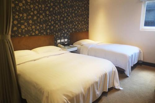 two beds in a hotel room with white sheets at Hotel Puri in Taipei