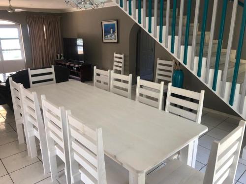 a white table and chairs in a room with a staircase at Caribbean Estates Villa 26 Calypso Drive in Port Edward