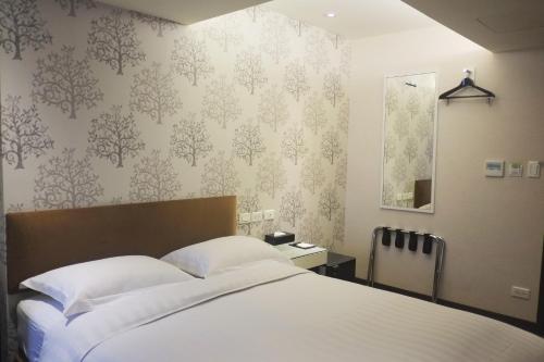 a bedroom with a bed with white sheets and wallpaper at Hotel Puri in Taipei