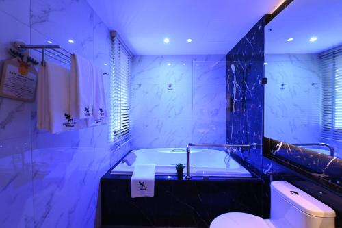 a bathroom with a tub and a toilet and a sink at Moose Hotel Nimman in Chiang Mai