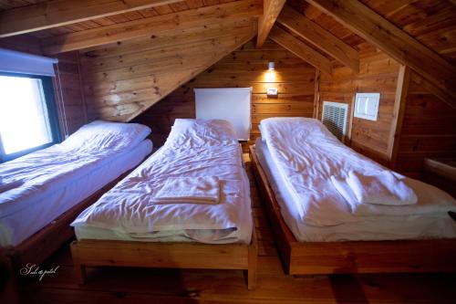 two beds in a wooden cabin with a window at ווילו בערבה in ‘En Yahav