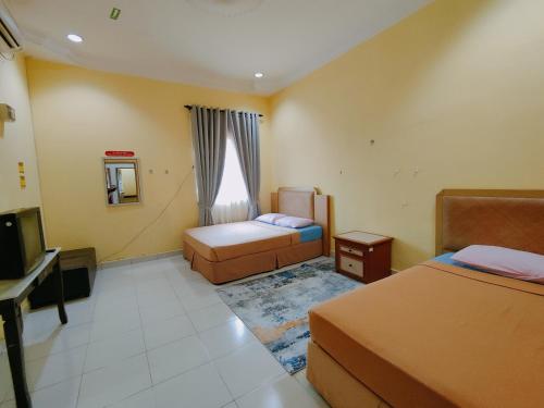 ein Hotelzimmer mit zwei Betten und einem Fernseher in der Unterkunft Homestay Roma Suite in Kuala Terengganu