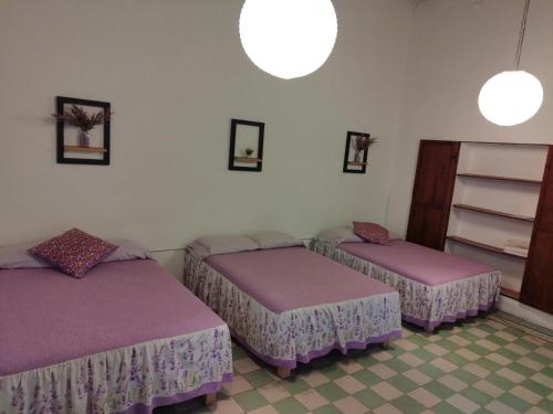 three beds in a room with purple sheets at Lavanda Centro Histórico de Querétaro in Querétaro