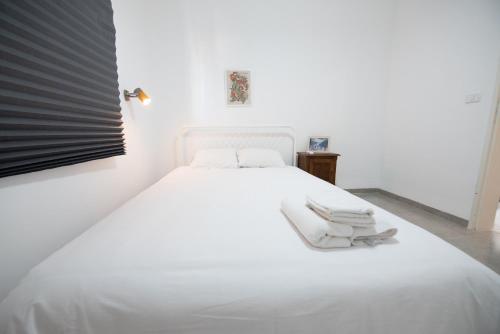 a white bed with white sheets and towels on it at PORT CITY HAIFA - Bat Galim 20m from the beach in Haifa