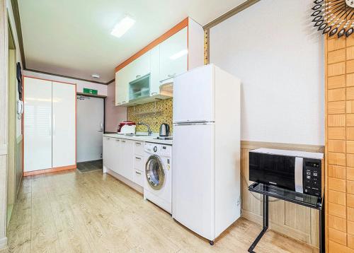 a kitchen with a white refrigerator and a microwave at Ddeulae Pension in Suncheon
