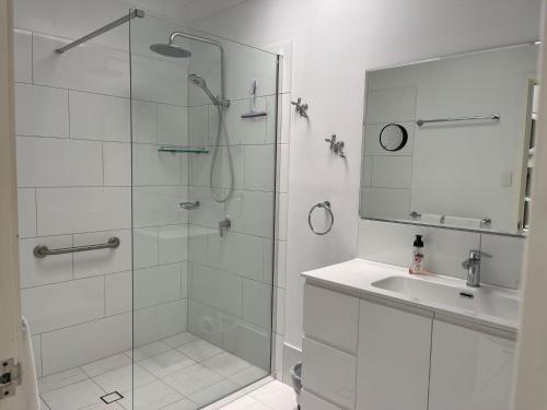 baño blanco con ducha y lavamanos en Magnetic Shores Unit 2, en Arcadia