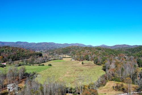an open field with trees and mountains in the background at Highland Harmony in Ellijay
