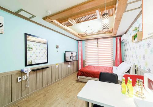 a room with a bed and a table in a room at Ddeulae Pension in Suncheon