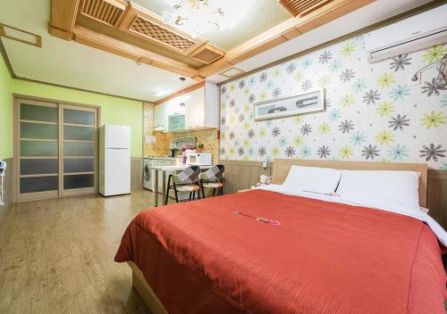 a bedroom with a red bed and a kitchen at Ddeulae Pension in Suncheon