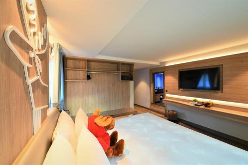 a teddy bear sitting on a bed in a room at Moose Hotel Nimman in Chiang Mai