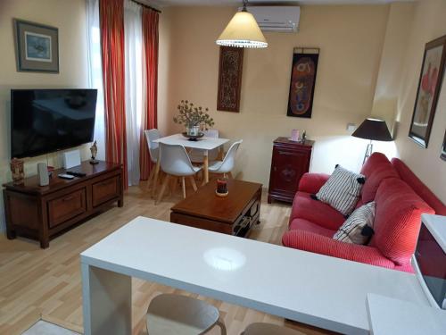 ein Wohnzimmer mit einem roten Sofa und einem TV in der Unterkunft Apartamento la Concha in Chiclana de la Frontera