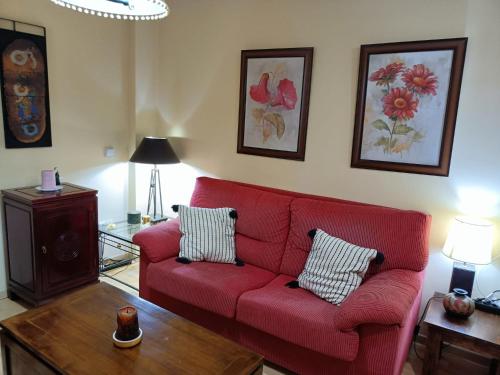 ein Wohnzimmer mit einem roten Sofa und einem Tisch in der Unterkunft Apartamento la Concha in Chiclana de la Frontera