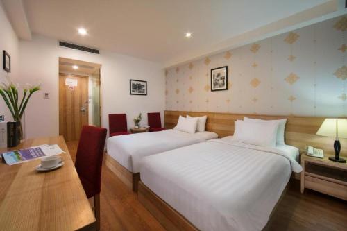 a hotel room with two beds and a table and a desk at Aviary Hanoi Hotel & Travel in Hanoi